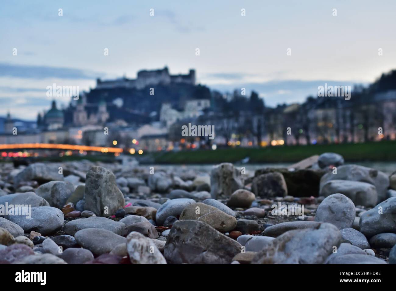 Kieselsteine an der Salzach mit der Stadt und der Festung Salzburg im Hintergrund Stockfoto