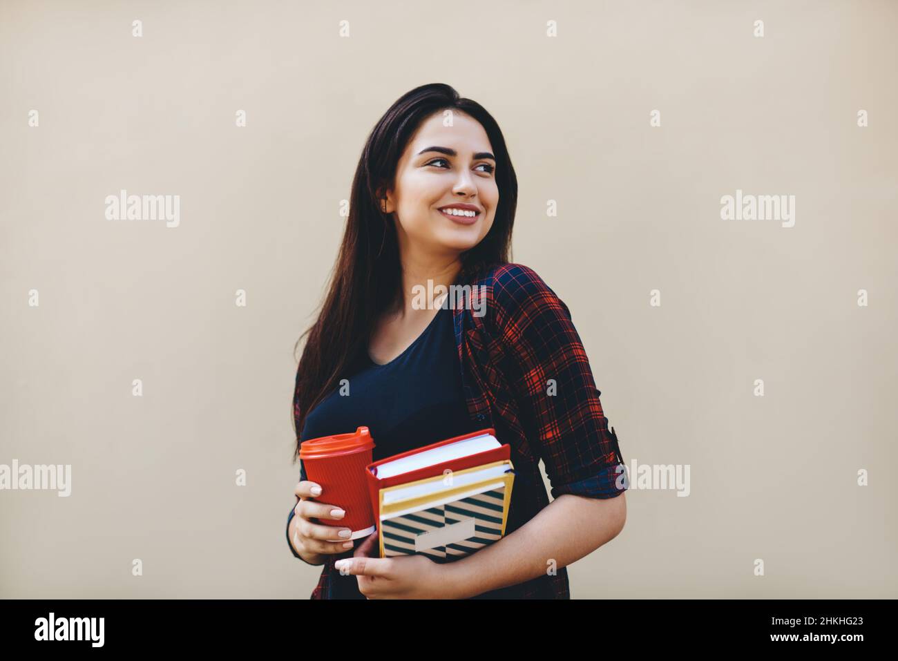 Glückliche Frau mit Büchern gegen beige Wand Stockfoto