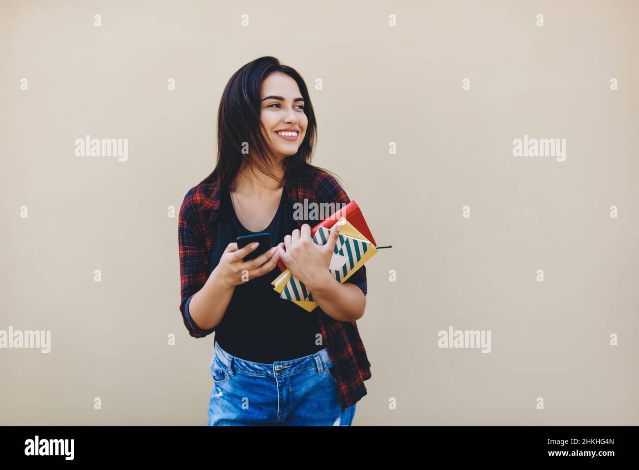 Glückliche Frau mit Notizbuch an beigefarbener Wand Stockfoto