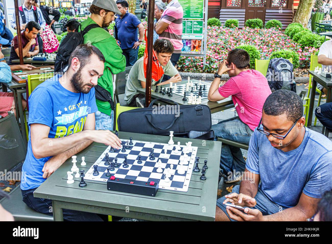 New York City, NY NYC, Manhattan, Midtown, Bryant Park Spiel Schach spielen Brett, schwarzer Mann Lesen SMS Messaging Smartphone Multitasking Stockfoto