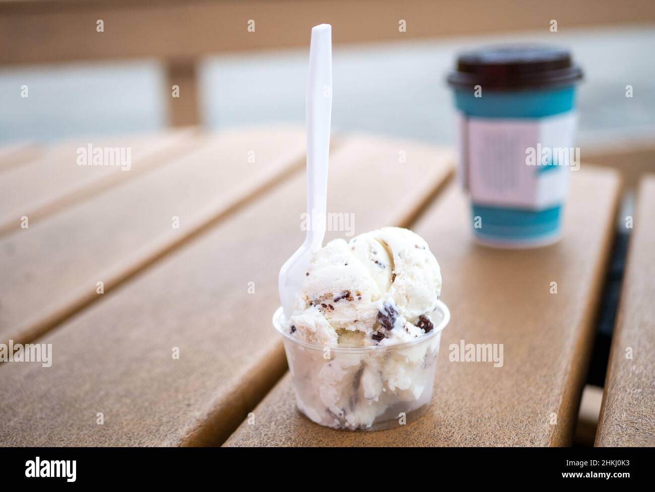 Plastiklöffel und -Tasse mit Vanille- und Schokoladenchip-Eis auf dem Picknicktisch Stockfoto