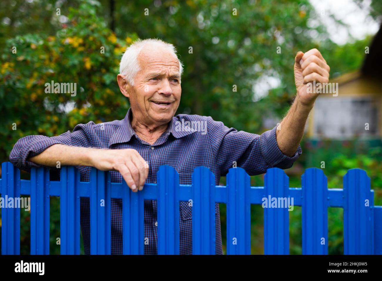 Alter Mann zeigt Faust im Freien neben dem Zaun Stockfoto