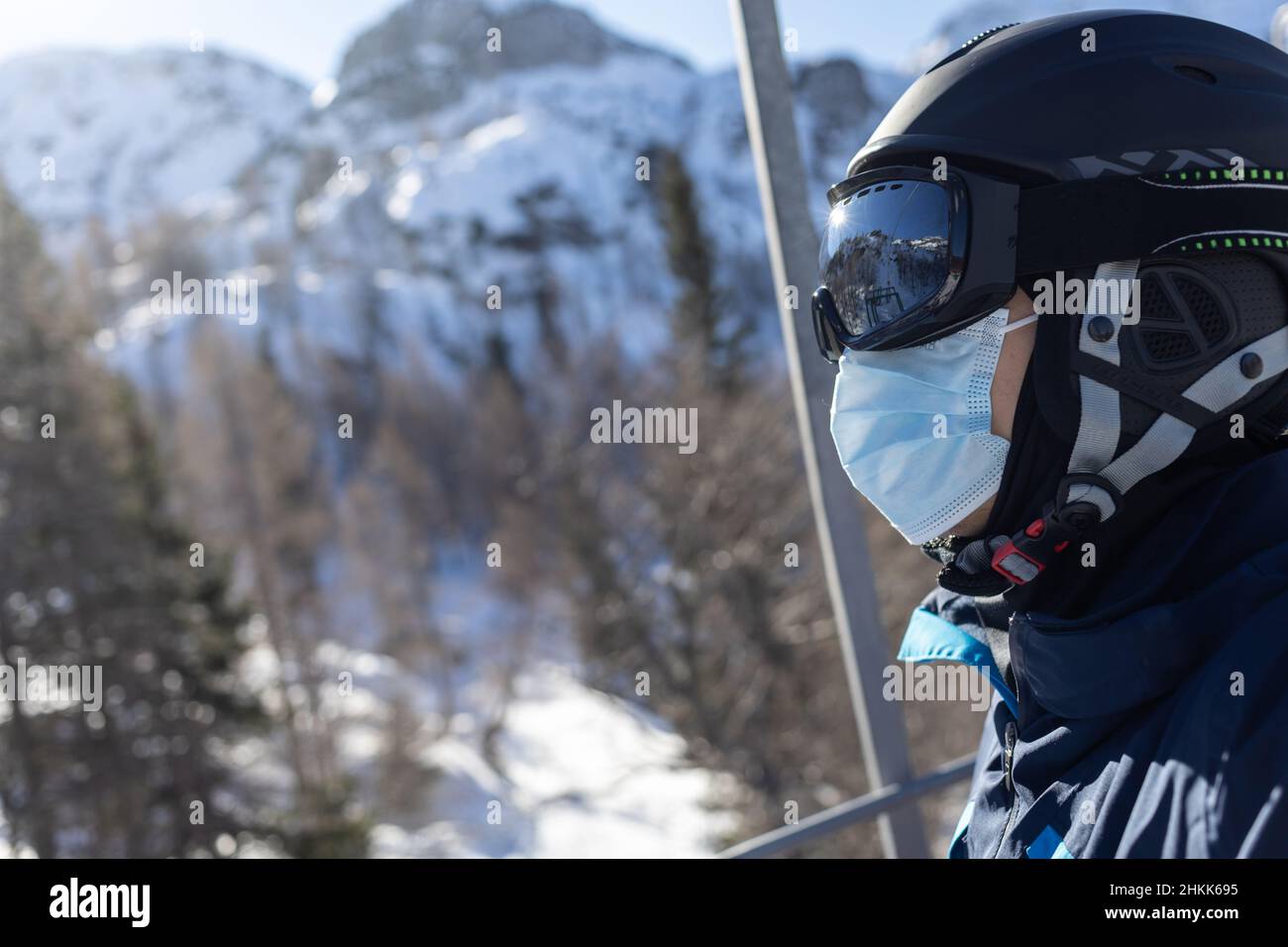 Skiresortmann auf Sessellift in Helm und medizinischer Maske Stockfoto