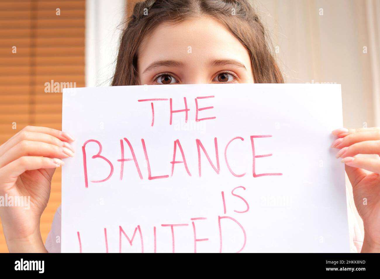 Junge Frau hält das Papier mit einem Schild nicht mehr Geld zu zahlen und bedeckt ihr Gesicht mit ihm, Probleme im Zahlungskonzept. Stockfoto