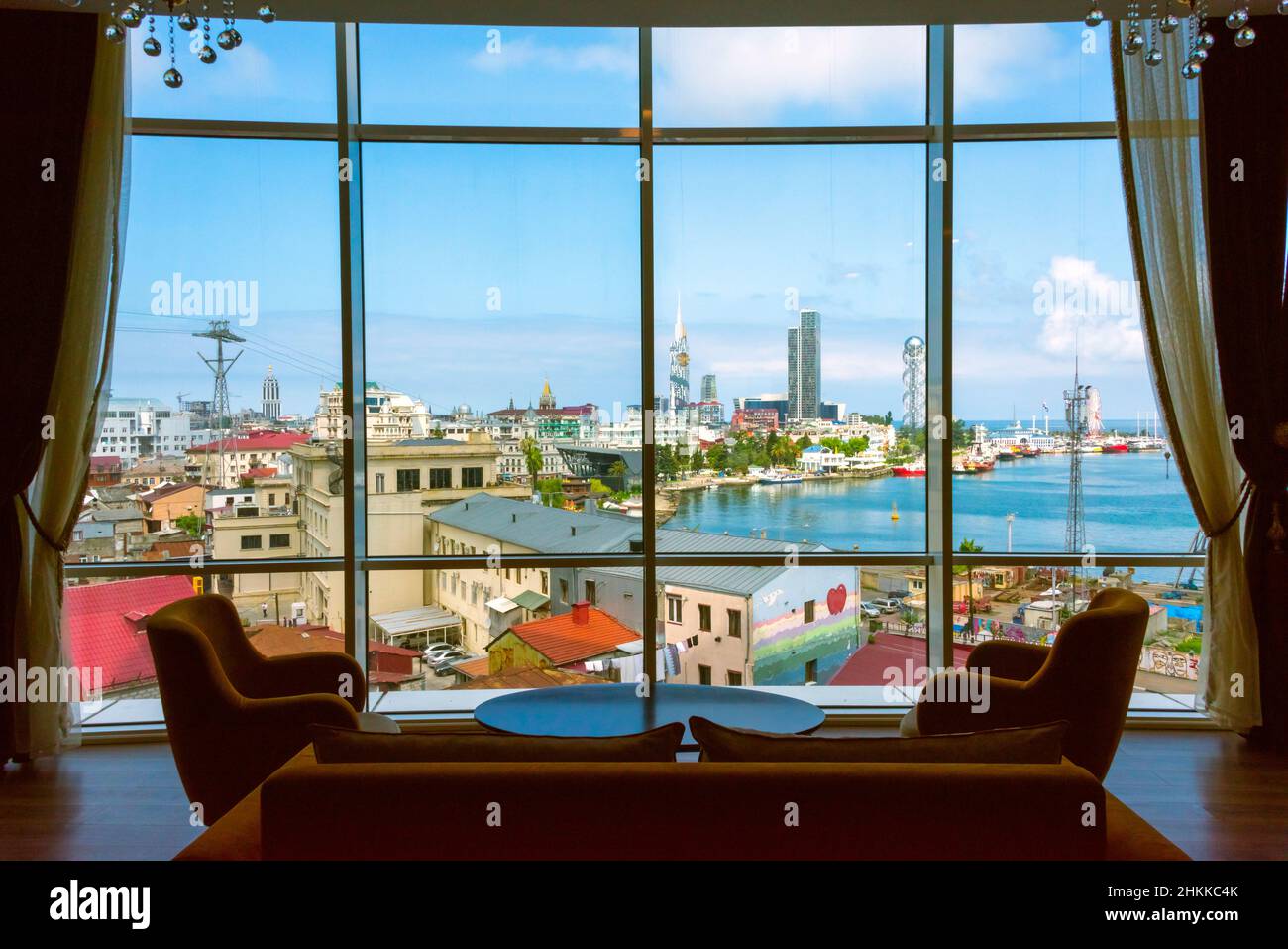 Blick auf das Stadtbild entlang der Küste des Kaspischen Meeres durch Fenster, Batumi Technological University Tower mit einem in die Fassade eingebauten Riesenrad, Stockfoto