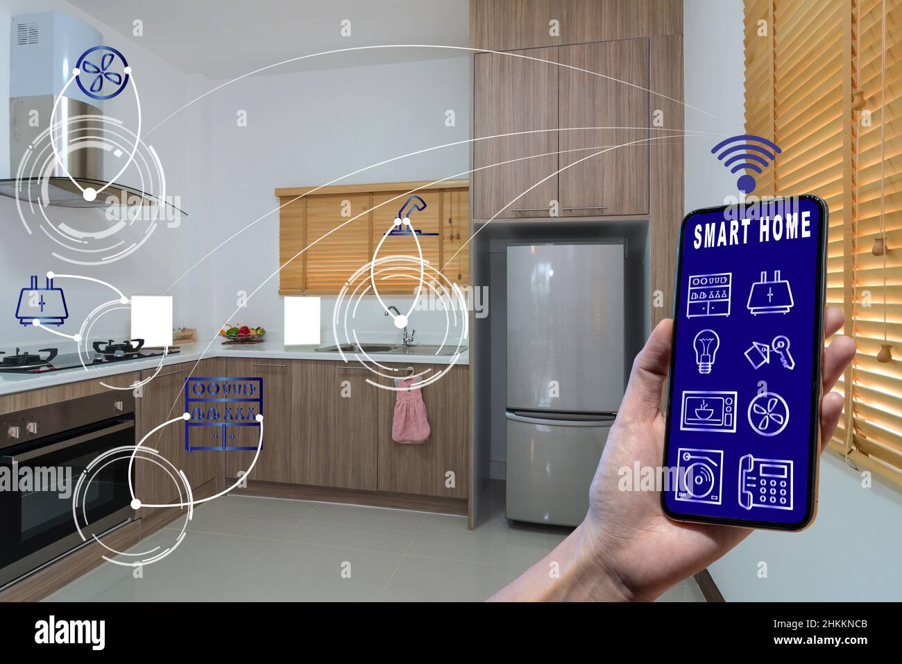 Smart Home- und Augmented Reality-Technologiekonzept, das Smartphone mit der Hand hält und den Smart Home-Bildschirm und das Symbol über der Luxus-Küche präsentiert Stockfoto