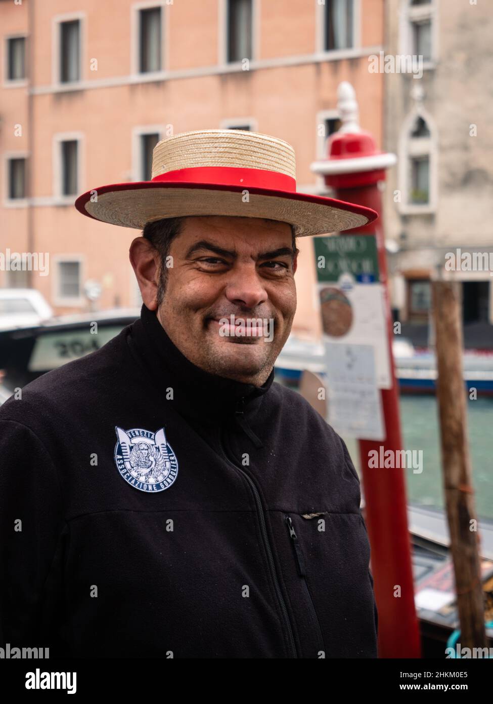 Venedig, Italien - Januar 5 2022: Gondoliere Bootsmann mit traditionellem Strohhut Portrait mit Logo der Associazione Gondolieri di Venezia Stockfoto