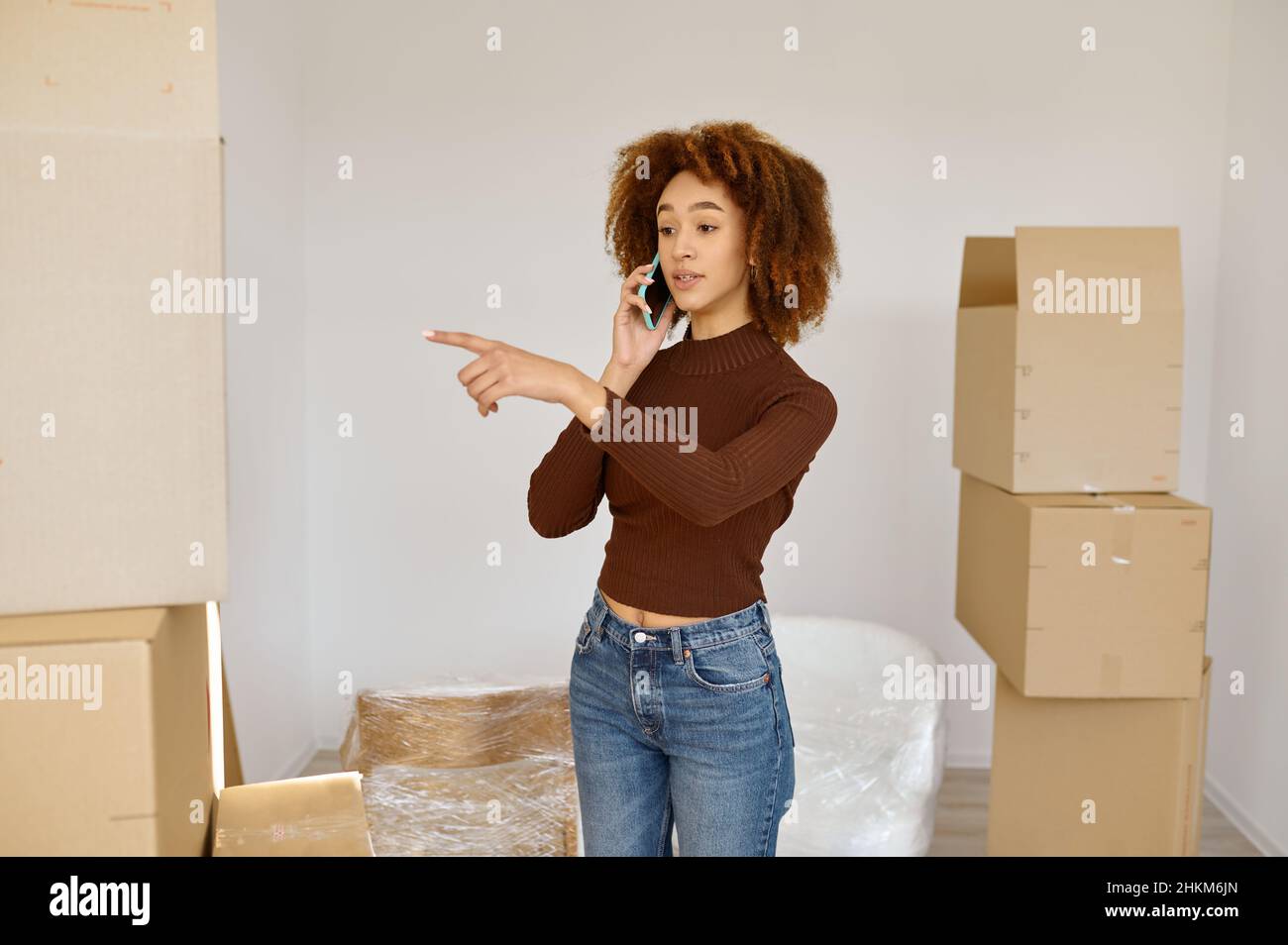Junge Frau telefoniert zwischen Kartons Stockfoto
