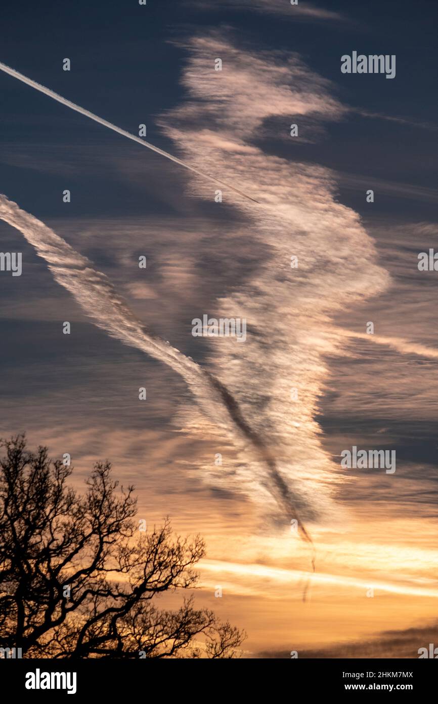 Ein Kreuzungsmuster aus Dampfspuren, das von hoch fliegenden Flugzeugen an einem kalten Morgen verursacht wird, schmückt den Himmel über Worcestershire, England. Stockfoto