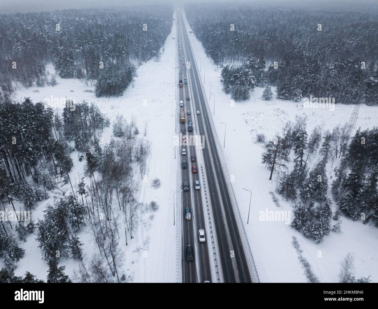 Eine Autobahn mitten in einem Winterwald. Blick aus der Höhe. Stau. Verlangsamung des Datenverkehrs. Stockfoto