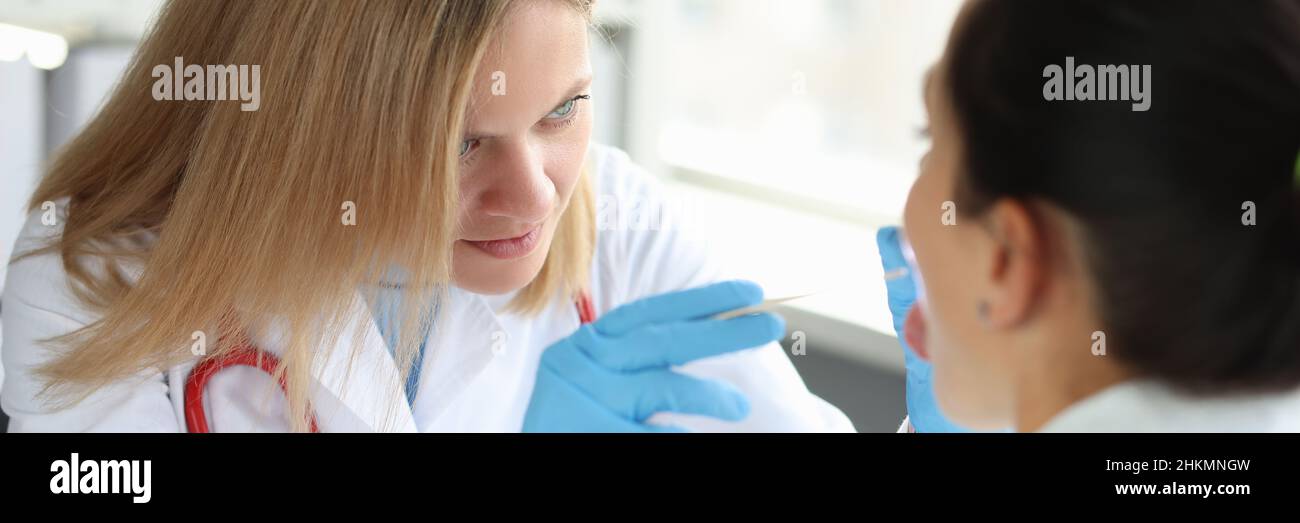 Der Arzt führt eine körperliche Untersuchung der Nahaufnahme des Kehlkopfes des Patienten durch Stockfoto
