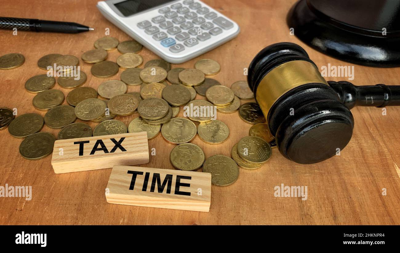 Tax Time Text auf Holzblöcken mit Münzen, Gavel, Taschenrechner Hintergrund. Steuerkonzept. Stockfoto