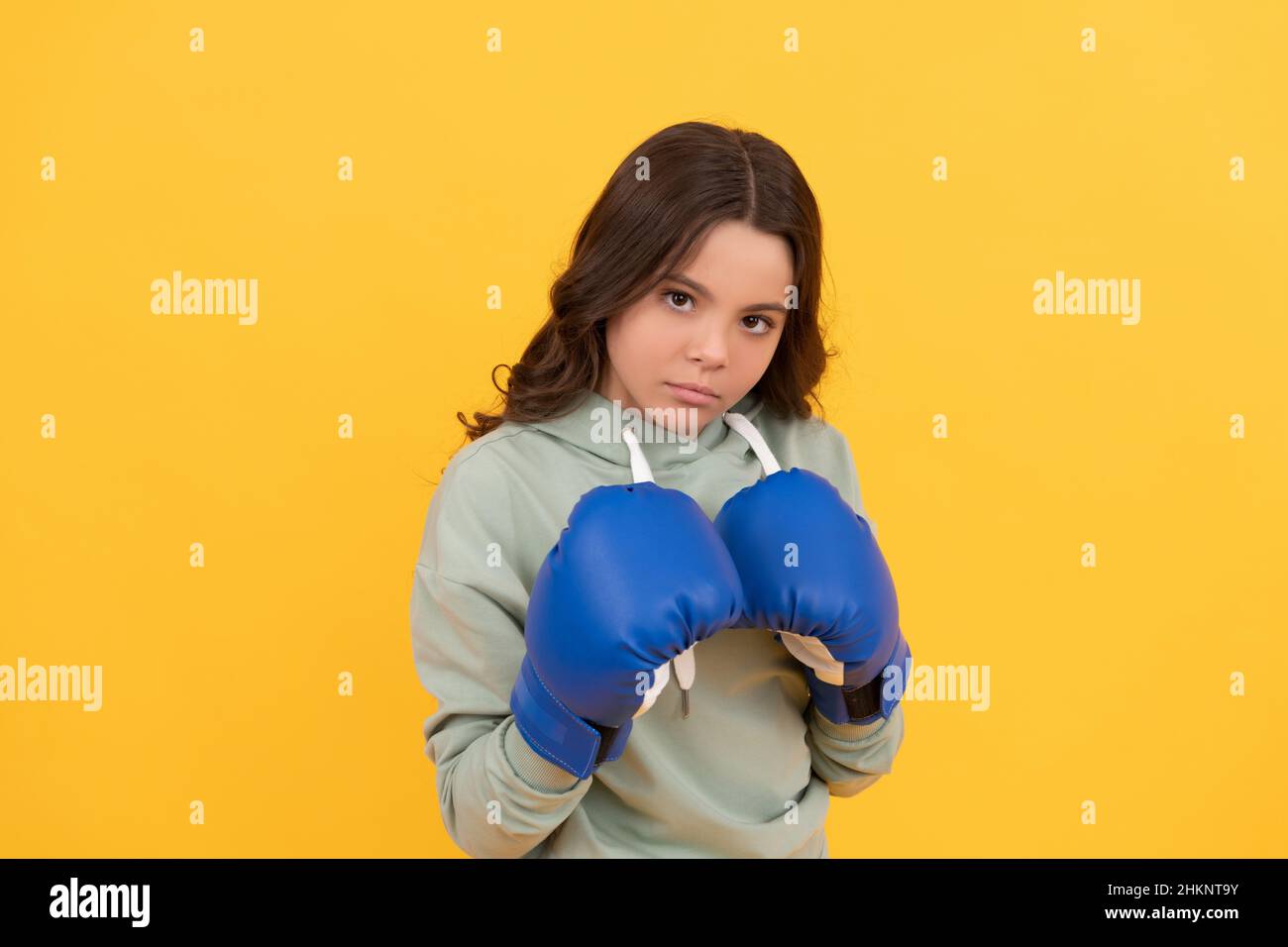 Ernsthaftes Kinderporträt in Boxhandschuhen auf gelbem Hintergrund Stockfoto