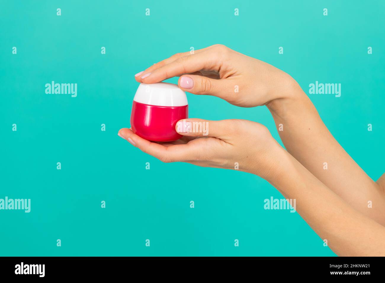 Weibliche Hände halten Hautcreme auf blauem Hintergrund. Beauty-Produkt Stockfoto