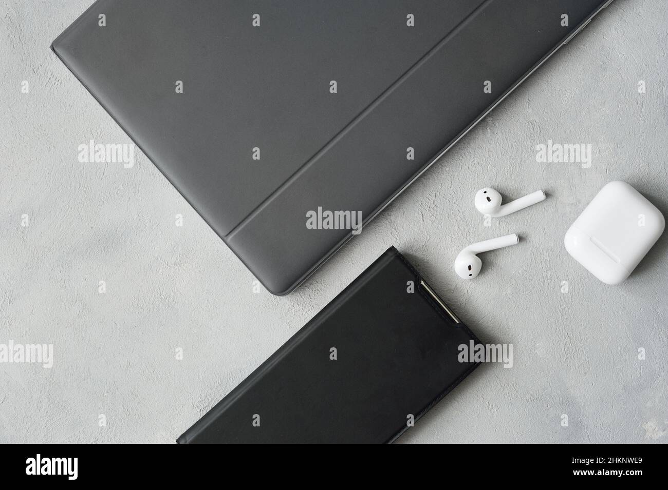 Flachbild des Arbeitsplatzes mit Laptop, Smartphone, Ohrhörern mit Kopierraum, grauer Hintergrund für Business-Design Stockfoto