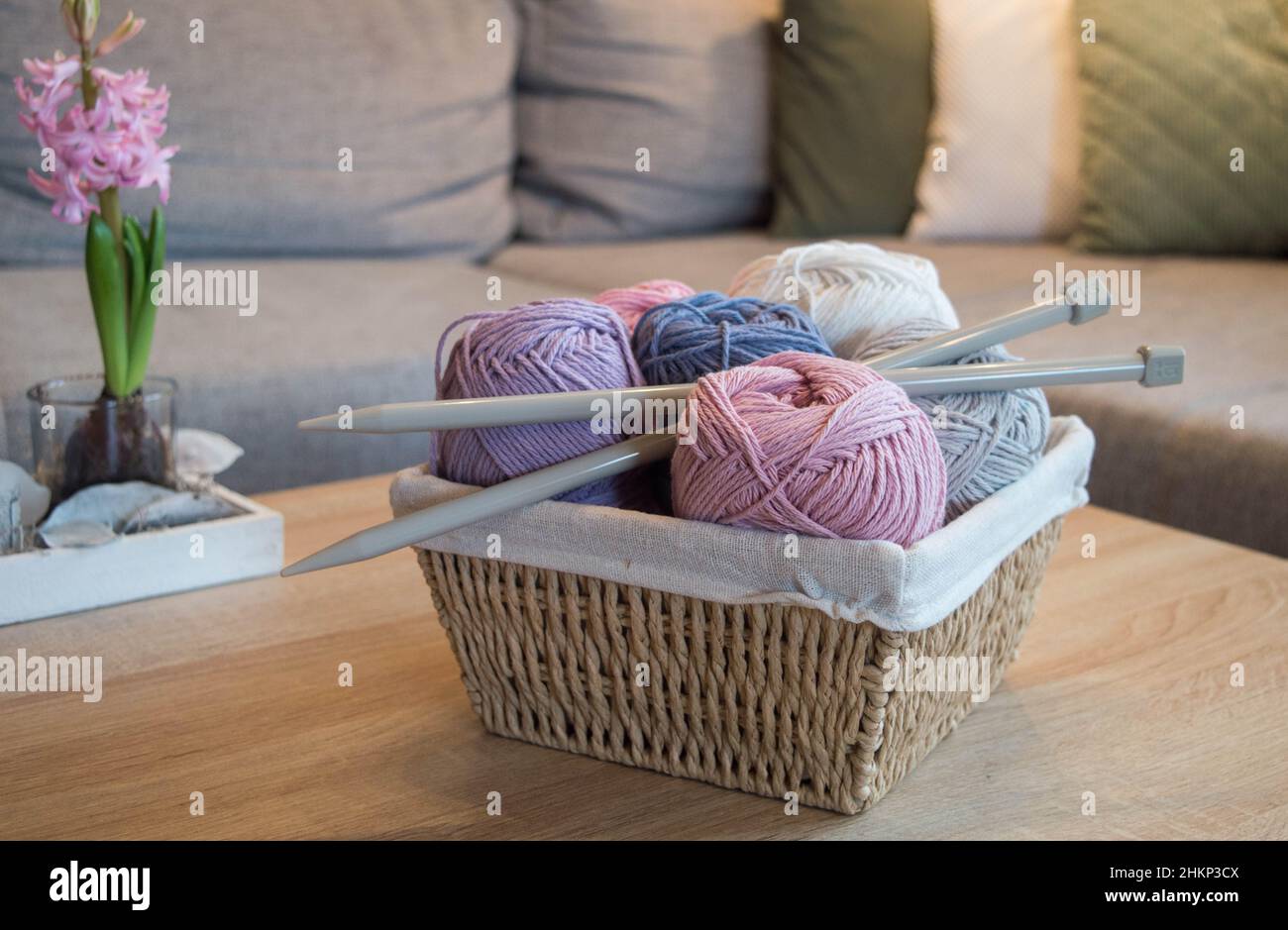 Bunte Wollkugeln in einem Holzkorb mit großen Stricknadeln handgefertigt Stockfoto