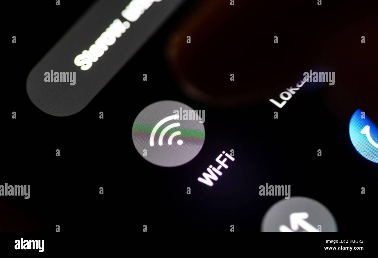 Finger einschalten des WiFi-Moduls auf einem Smartphone, Mobiltelefon-Display, Touchscreen-Details, Nahaufnahme, Makro, Im Dunkeln. WiFi Wireless Network Inter Stockfoto