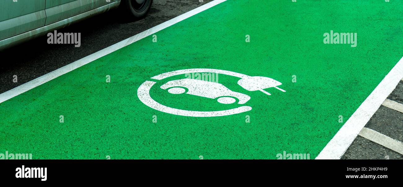 Leerer Parkplatz für Elektrofahrzeuge, grüne Zone markiert, Autoladegerätesymbol auf dem Asphalt, niemand. Umweltfreundlich, umweltfreundlich Stockfoto