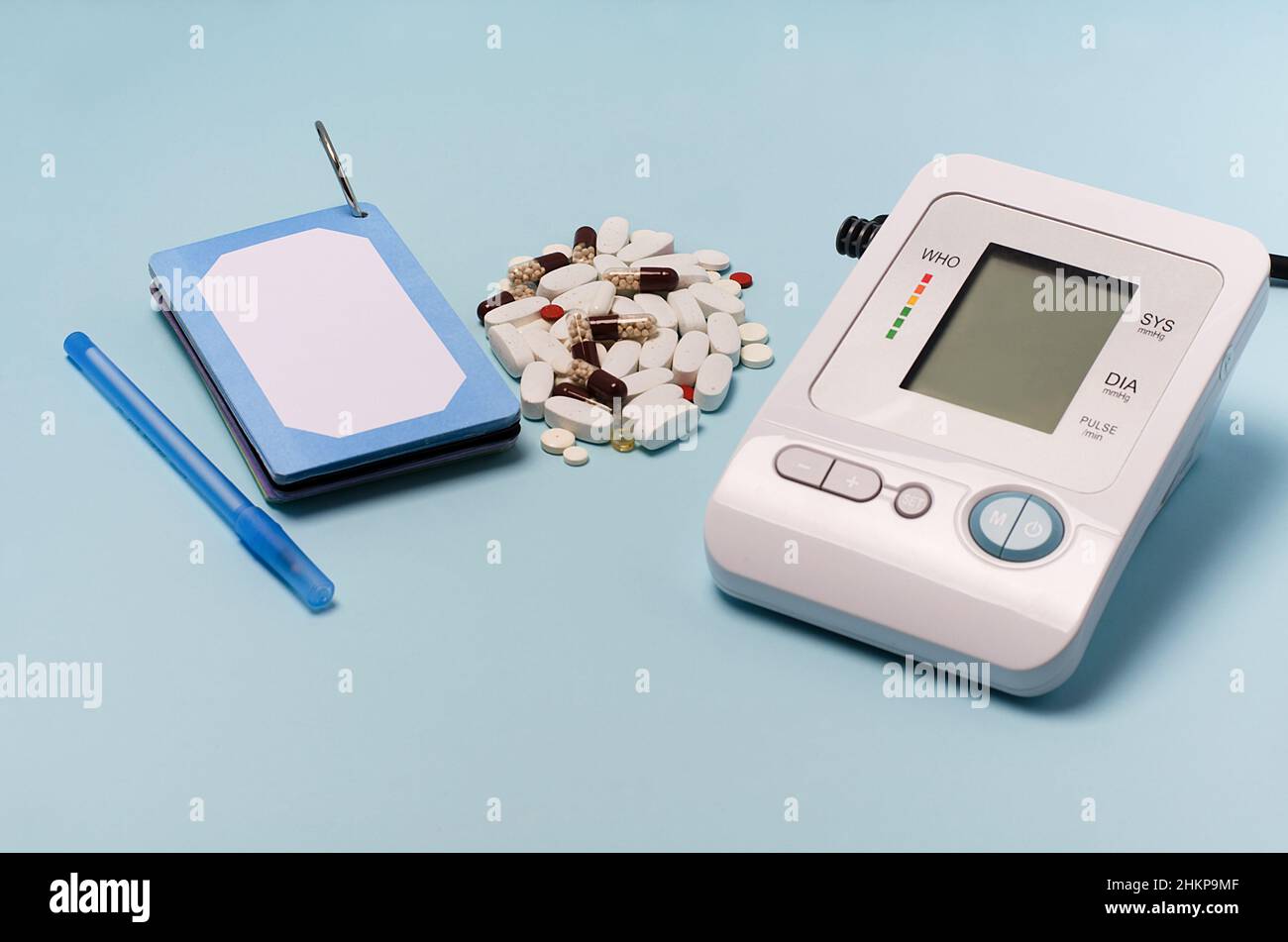 Ein Gerät zur Druckmessung, ein Tonometer auf blauem medizinischen Hintergrund, eine Handvoll Pillen.Kopfschmerzen, Behandlung von Bluthochdruck, Hypotonie. Stockfoto