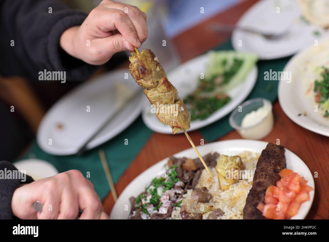 Im libyschen Restaurant hält ein Mann Kebab-Spieß Stockfoto