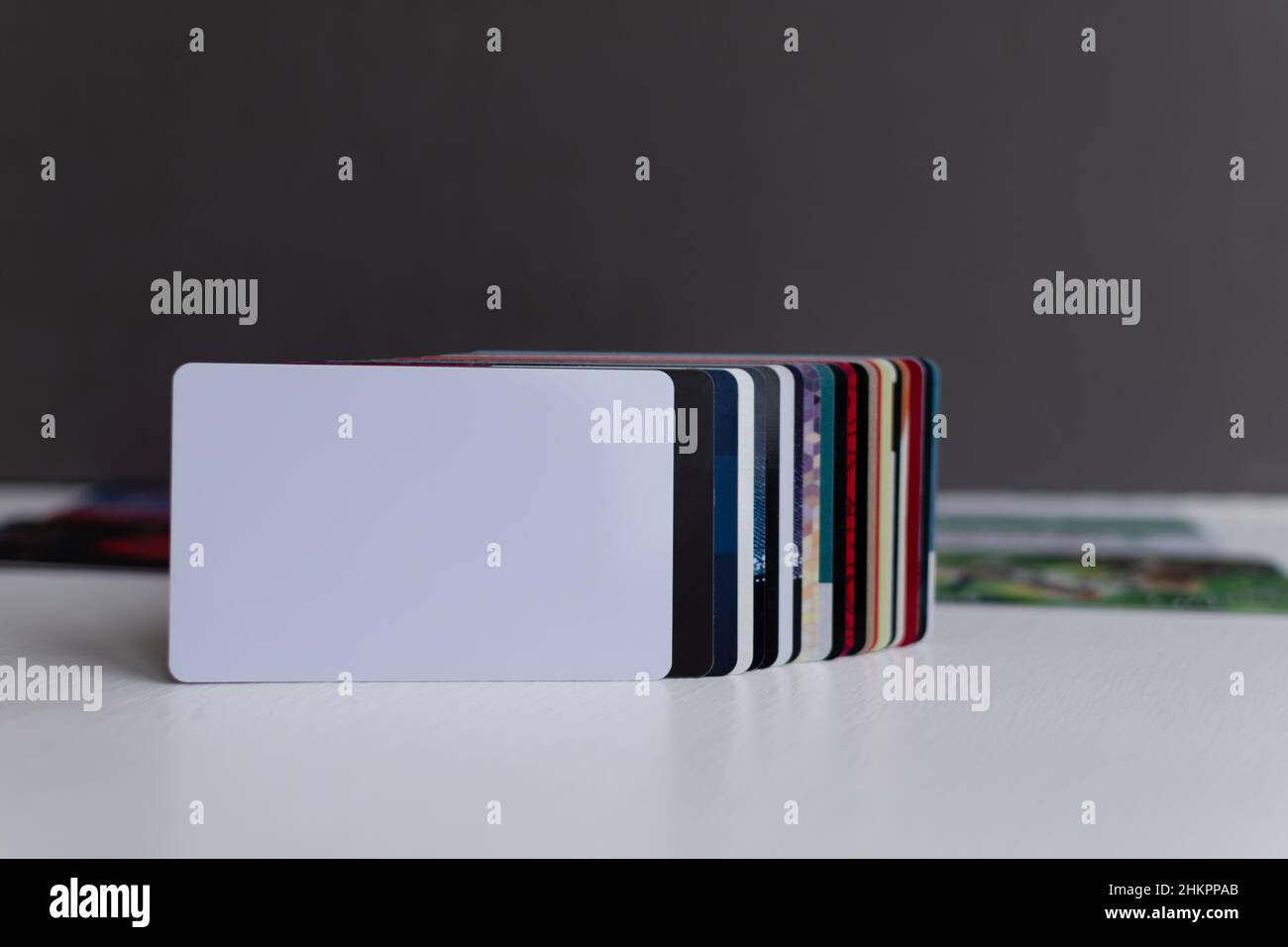 Leere weiße Plastikkarten-Nahaufnahme im Vordergrund in einer Reihe anderer Plastikkarten für Kundentreue auf verschwommenem grau-weißem Hintergrund Stockfoto