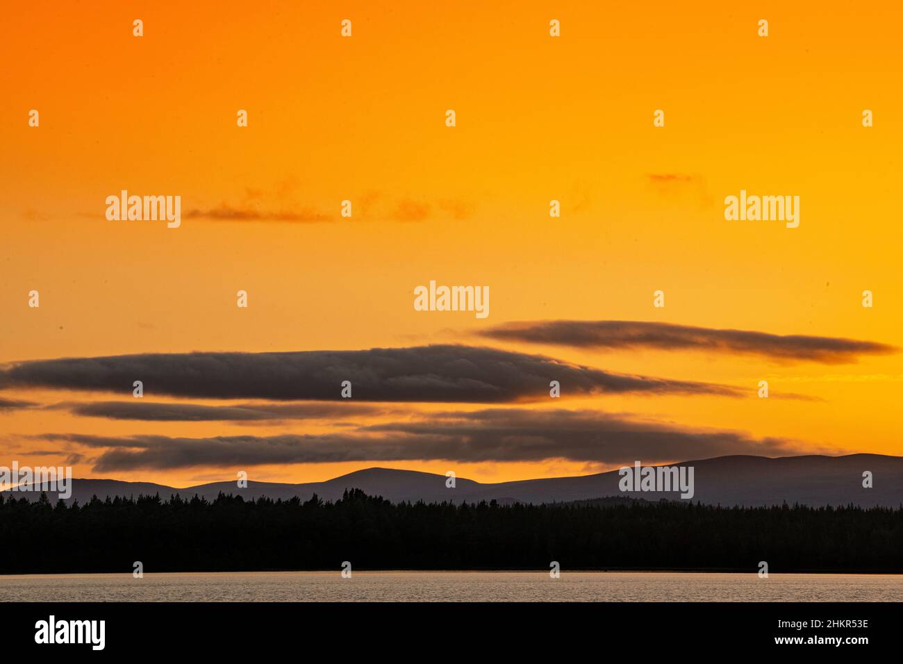 Die Sonne untergeht hinter den Hügeln über Loch Morlich in den schottischen Highlands Stockfoto
