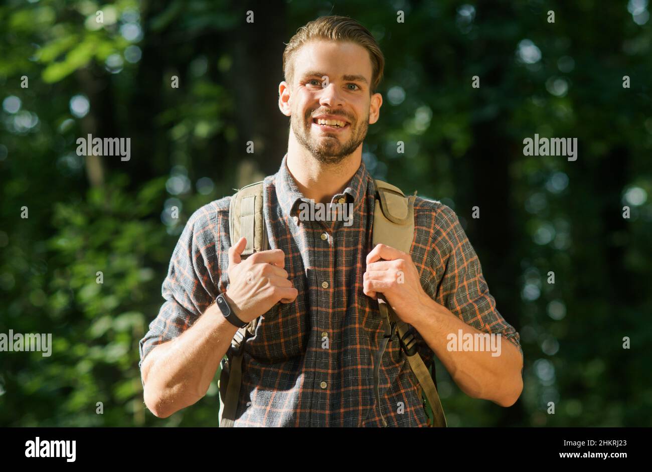Lächelnder Mann mit Rucksack, der allein in der Naturlandschaft unterwegs ist. Tourismuskampagne. Spaziergang im Wald. Stockfoto