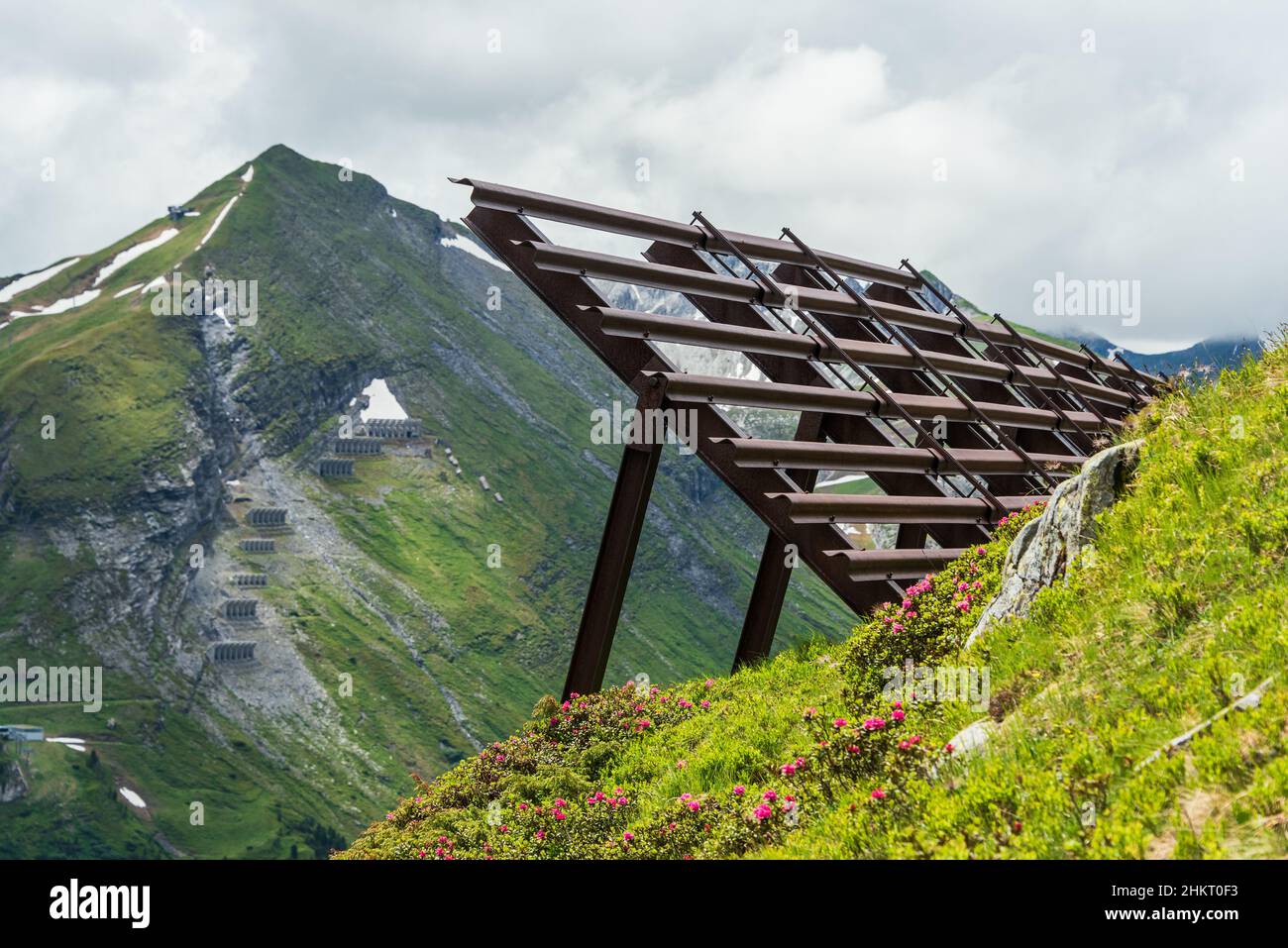 Lawinenschutzzäune in den alpinen Bergen. Stahlschneebrücken und gleitende Schneeständer. Sommer Berglandschaft. Stockfoto