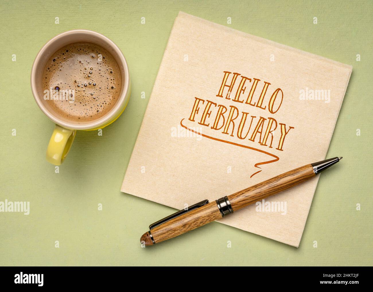 Hallo Februar - Handschrift auf Serviette mit einer Tasse Kaffee, warme Pastelltöne Stockfoto