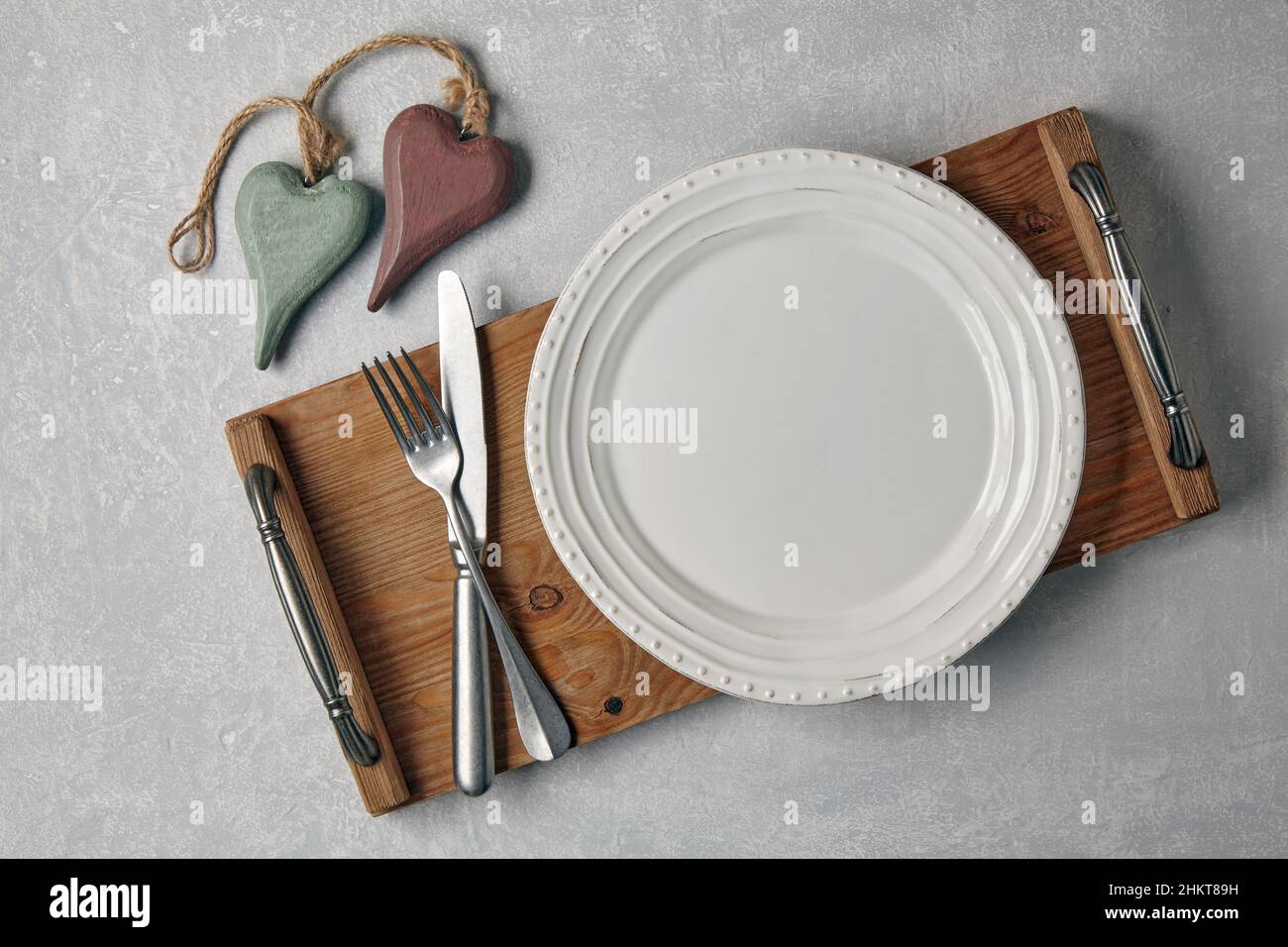Leeren Sie den weißen Teller mit Besteck auf einem Holztablett Stockfoto