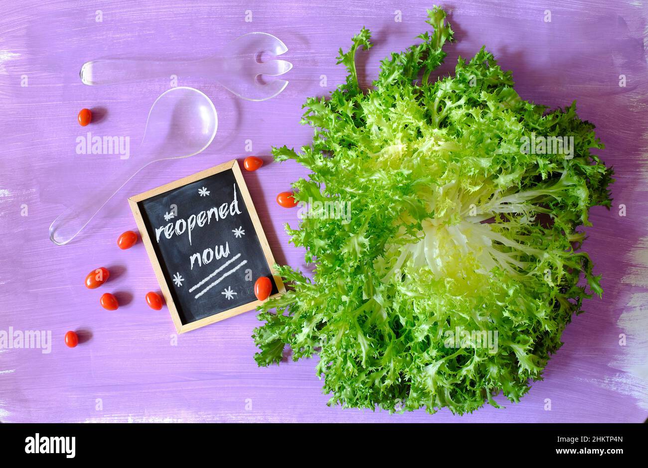 Restaurant wieder öffnen Schild mit Endive, Tomaten und zwei Salatbedienern, Wiederaufnahme des Geschäfts nach der Corona-Sperre, Konzept. Stockfoto