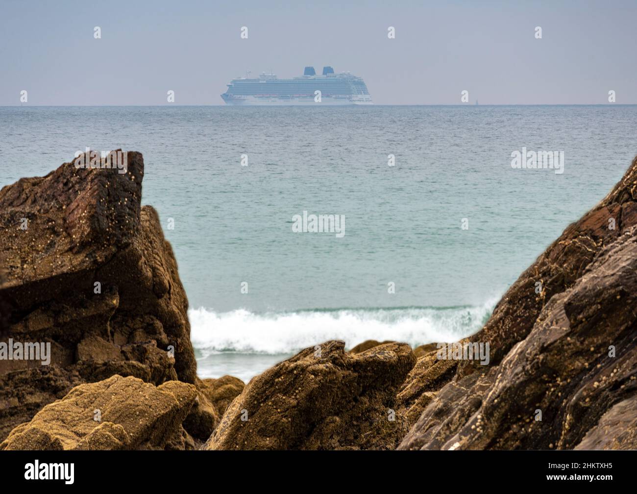 Während der Sommerferienzeit, sanft fokussierte Figur eines Schiffes am Horizont, auf ruhigem Wetter Atlantischer Ozean, eingerahmt zwischen felsigen Zinnen im Stockfoto