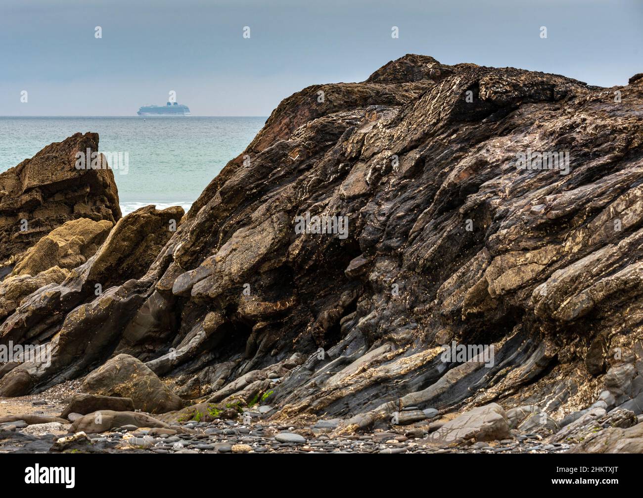 Während der Sommerferienzeit, sanft fokussierte Figur eines Schiffes am Horizont, auf ruhigem Wetter Atlantischer Ozean, eingerahmt zwischen felsigen Zinnen im Stockfoto
