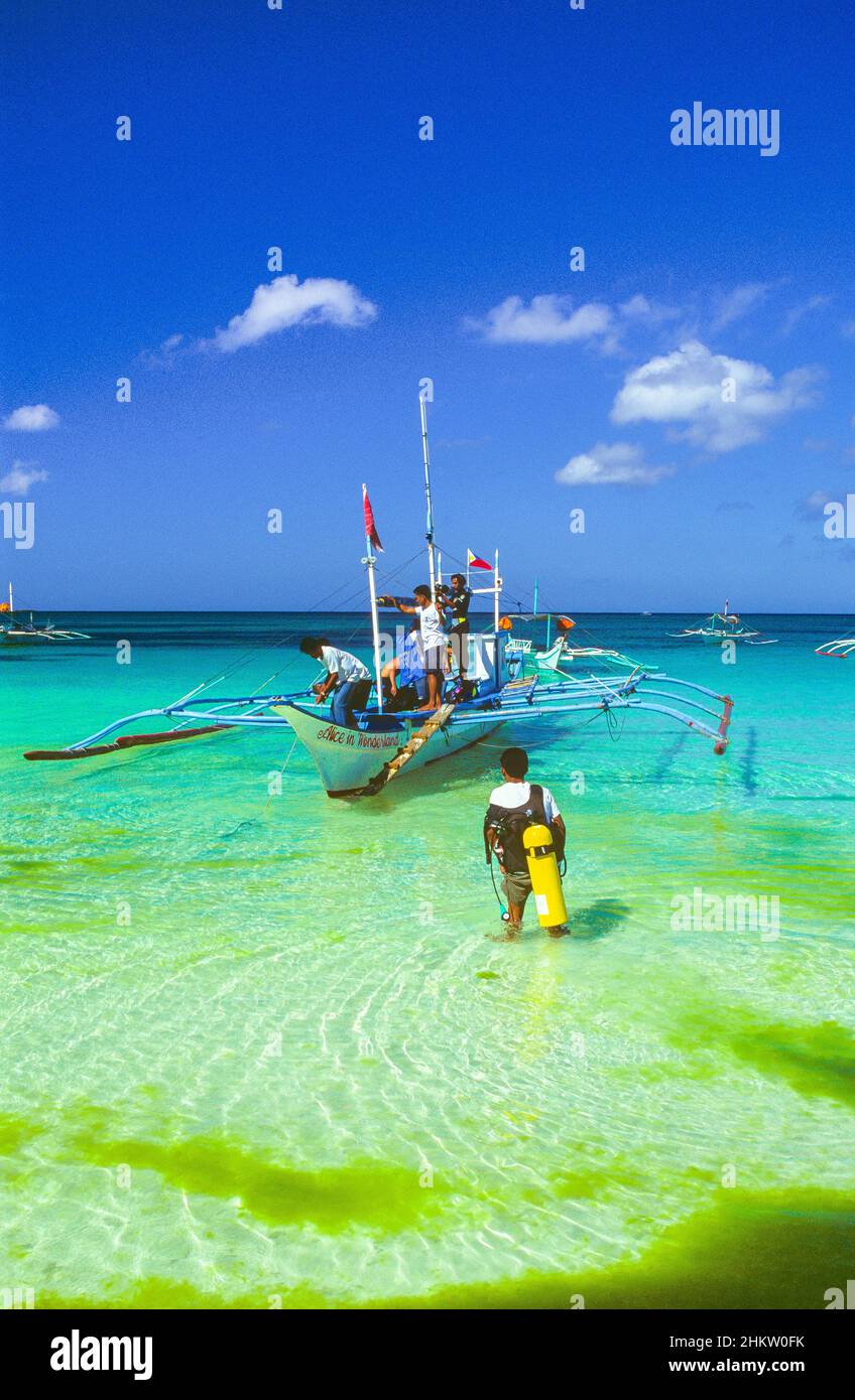 Segler und Taucher bereiten ein traditionelles philippinisches Auslegerboot vor, das am White Beach auf der Insel Boracay in der Region Western Visayas auf den Philippinen festgemacht ist. Stockfoto