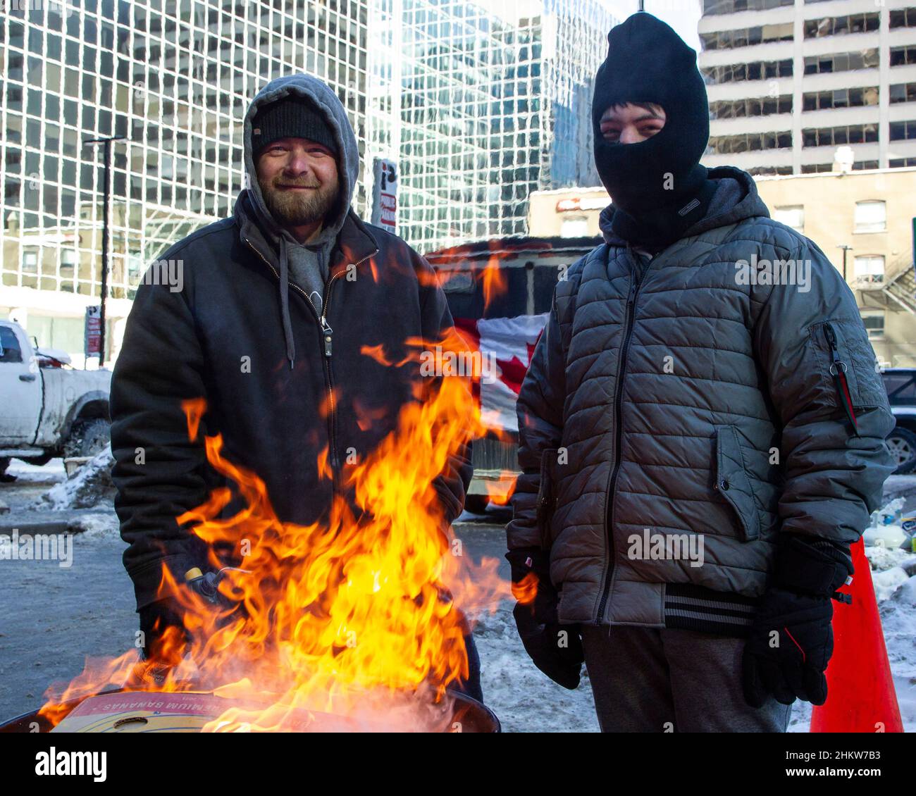 Zwei Demonstranten wärmen sich bei einem Öltrommelfeuer auf die Besatzung des Konvois 2022 im Stadtzentrum von Ottawa. Stockfoto