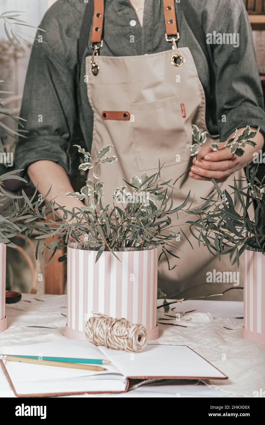 Florist machen Geschenk Sträuße in Hutboxen. Anmutige weibliche Hände machen einen schönen Strauß. Floristen-Arbeitsplatz. Konzept für kleine Unternehmen. Vertikale Aufnahme Stockfoto