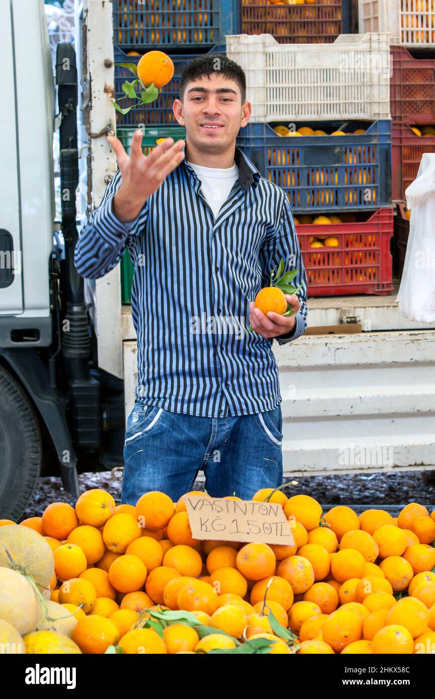 Ein türkischer Gemüsehändler, der Orangen auf dem Kas Freitagsmarkt verkauft. KAS ist ein Dorf am Mittelmeer in der Türkei. Stockfoto