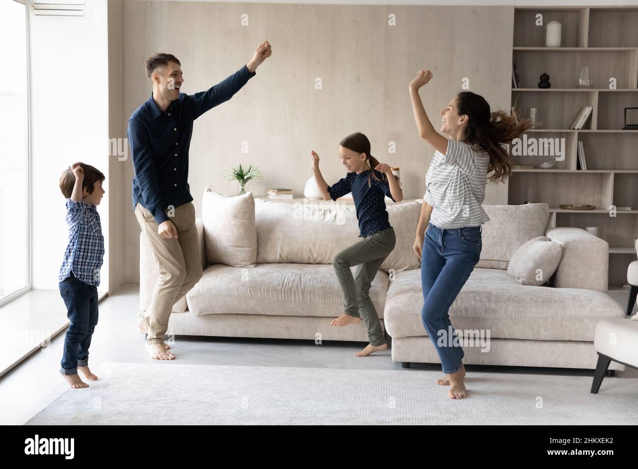 Glückliche Familie mit zwei Kindern, die im Wohnzimmer tanzen Stockfoto
