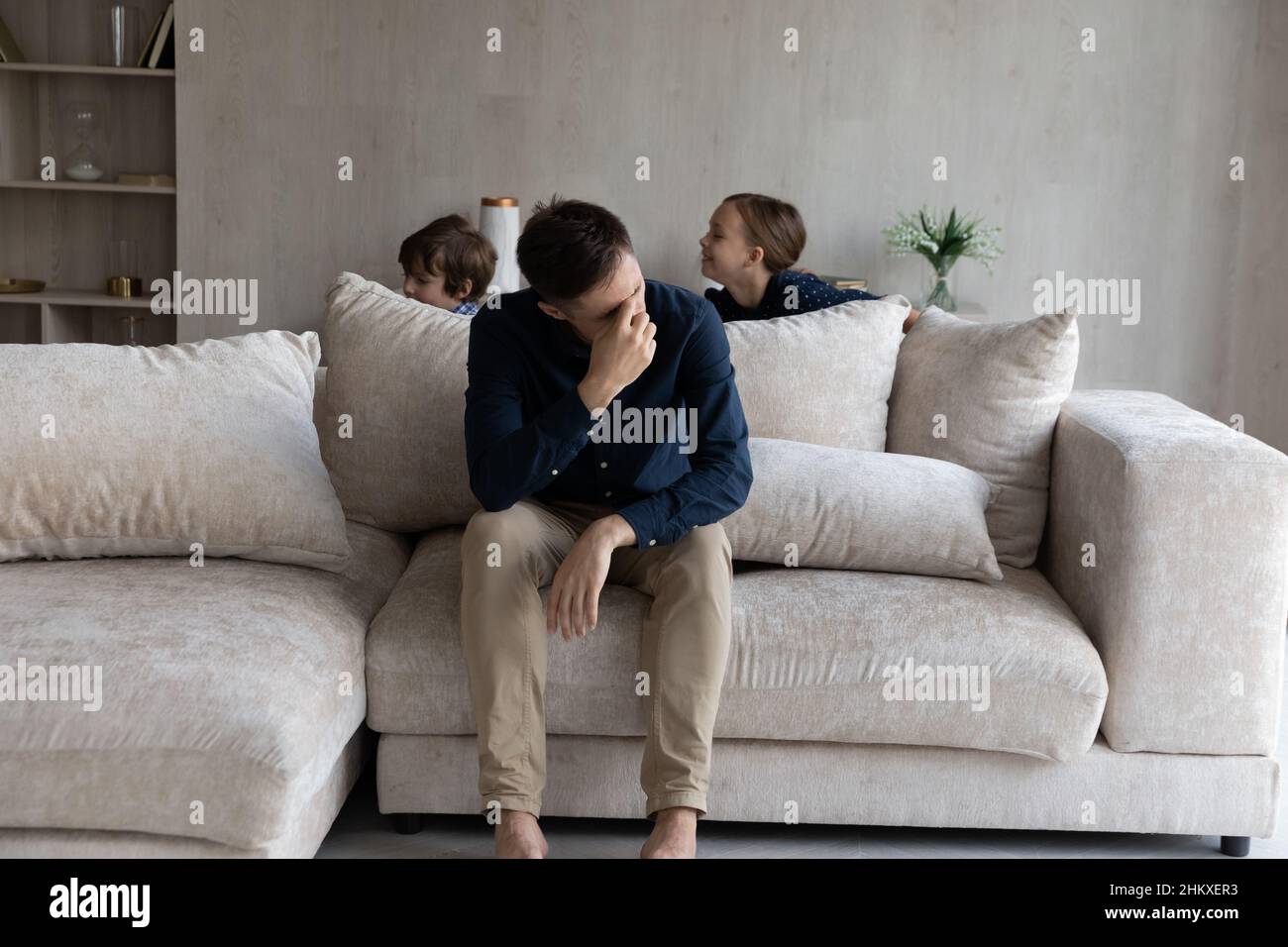 Müder Vater, der unter Kopfschmerzen leidet, erschöpft von lauten Kindern Stockfoto