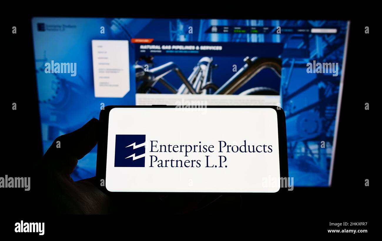Person, die Mobiltelefon mit dem Logo der Pipeline-Firma Enterprise Products Partners L.P. auf dem Bildschirm vor der Webseite hält. Konzentrieren Sie sich auf die Telefonanzeige. Stockfoto