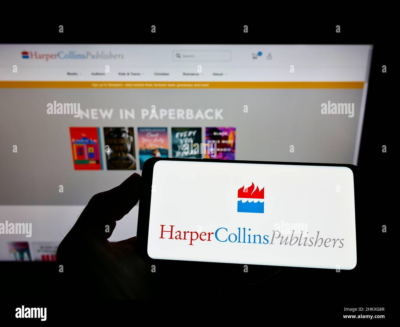 Person, die das Smartphone mit dem Logo der US-amerikanischen HarperCollins Publishers LLC auf dem Bildschirm vor der Website hält. Konzentrieren Sie sich auf die Telefonanzeige. Stockfoto