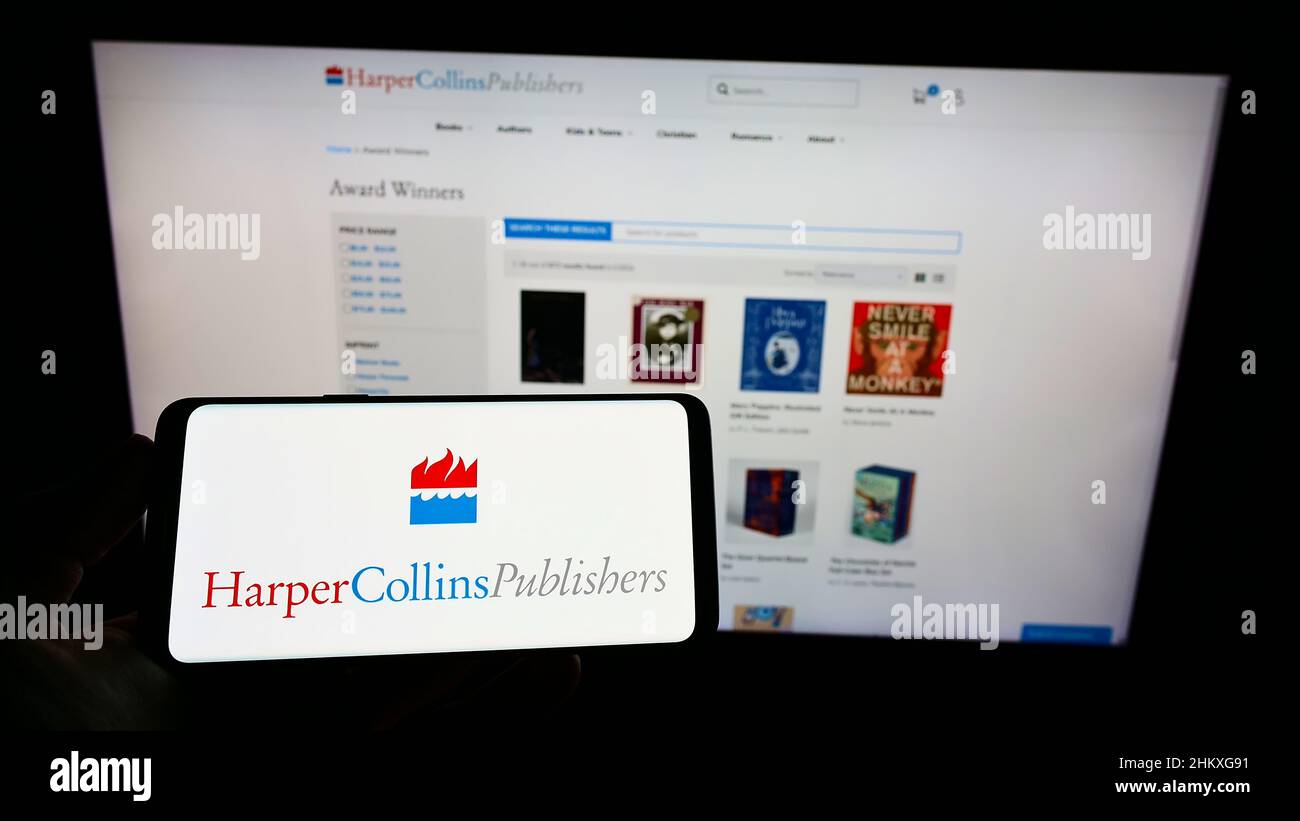 Person, die ein Mobiltelefon mit dem Logo der amerikanischen Firma HarperCollins Publishers LLC auf dem Bildschirm vor der Webseite hält. Konzentrieren Sie sich auf die Telefonanzeige. Stockfoto