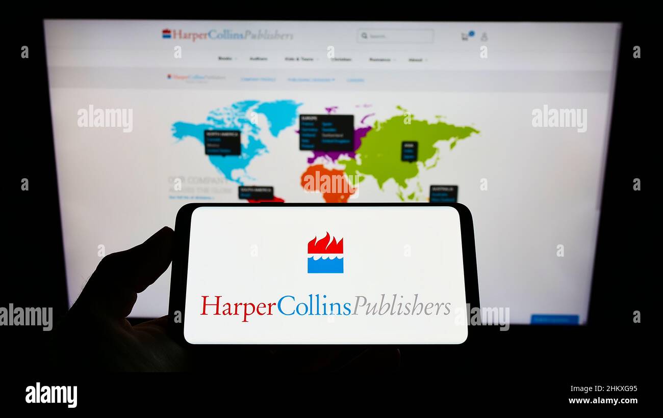 Person, die Mobiltelefon mit dem Logo des US-Unternehmens HarperCollins Publishers LLC auf dem Bildschirm vor der Geschäftswebseite hält. Konzentrieren Sie sich auf die Telefonanzeige. Stockfoto