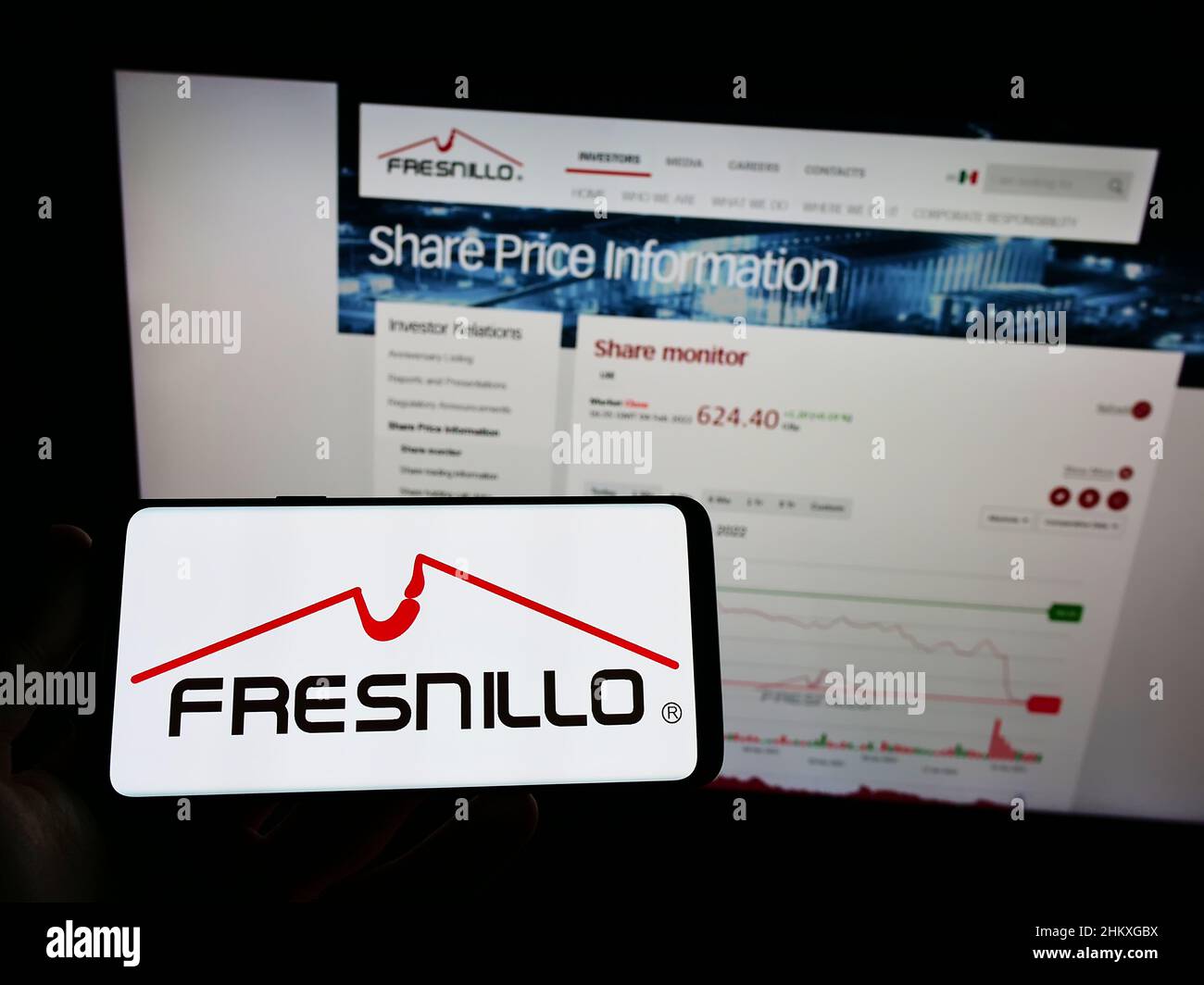 Person, die ein Mobiltelefon mit dem Logo des Bergbauunternehmens Fresnillo plc auf dem Bildschirm vor der Unternehmenswebseite hält. Konzentrieren Sie sich auf die Telefonanzeige. Stockfoto