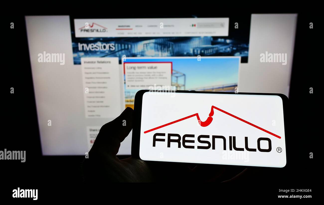 Person, die Mobiltelefon mit dem Logo des Metallbergbauunternehmens Fresnillo plc auf dem Bildschirm vor der Business-Webseite hält. Konzentrieren Sie sich auf die Telefonanzeige. Stockfoto