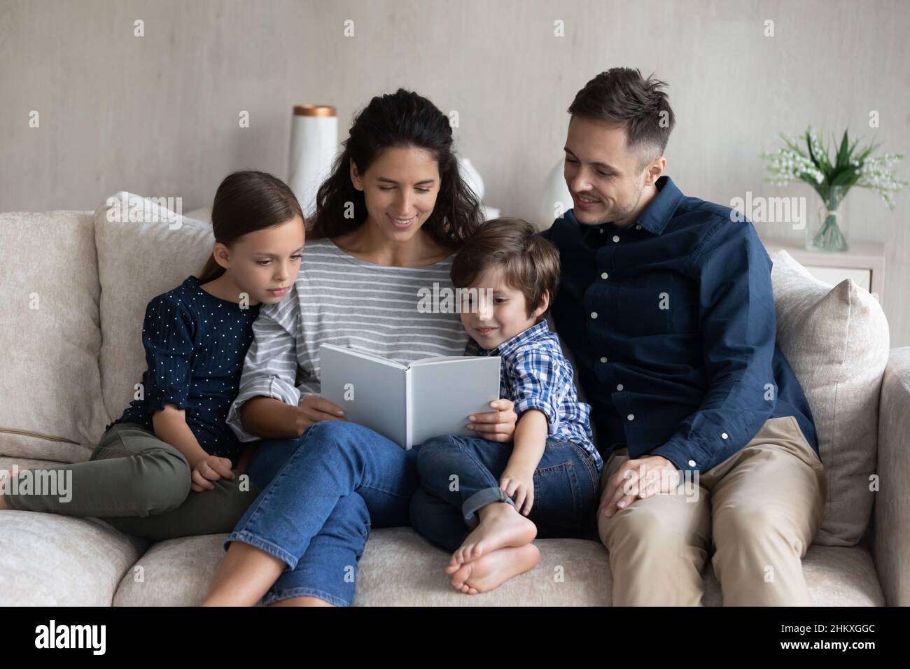 Fröhliche Familie, die zusammen Buch liest und sich auf der Couch entspannt Stockfoto