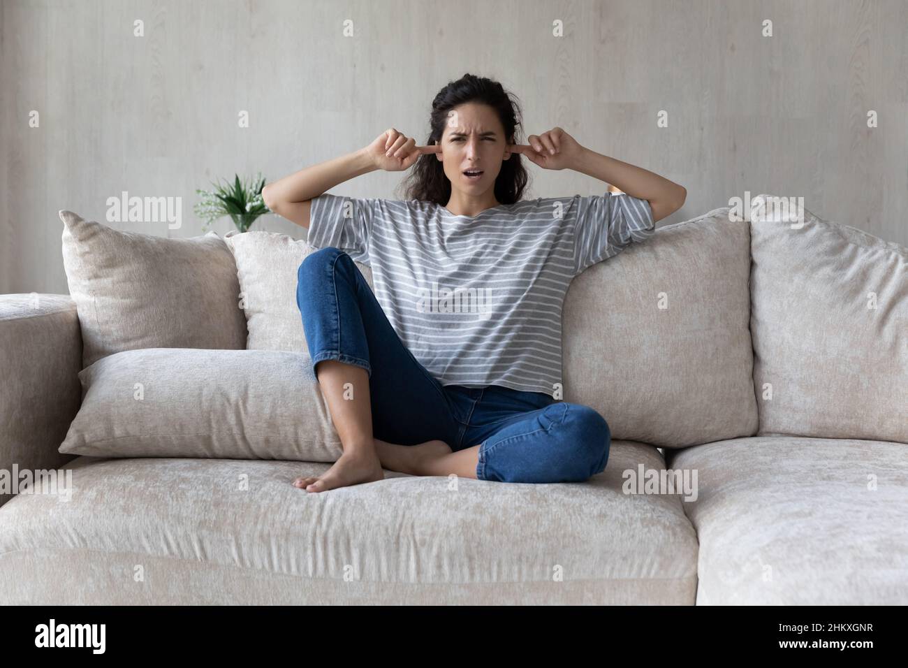 Verärgerte hispanische Frau, die Ohren mit den Fingern verstopfte, laute Nachbarn Stockfoto