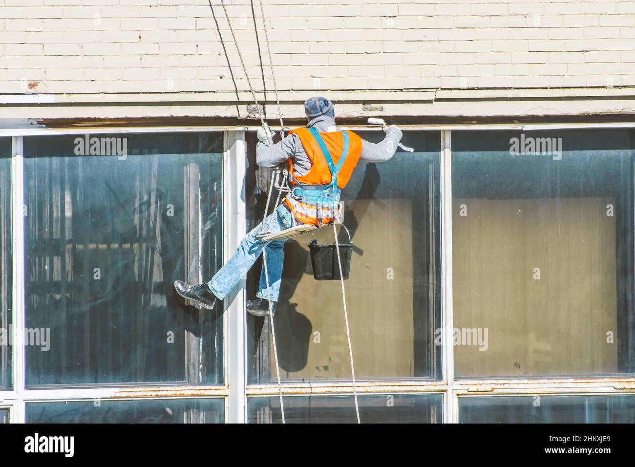 Industrial Mountaineering, ein Mann stellt Gelenke in Fenstern und wäscht sie Stockfoto