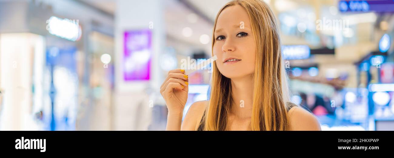 Eine Frau mit Papierstreifen in den Händen lauscht dem Duft auf dem LANGFORMATIGEN BANNER des Einkaufszentrums Stockfoto