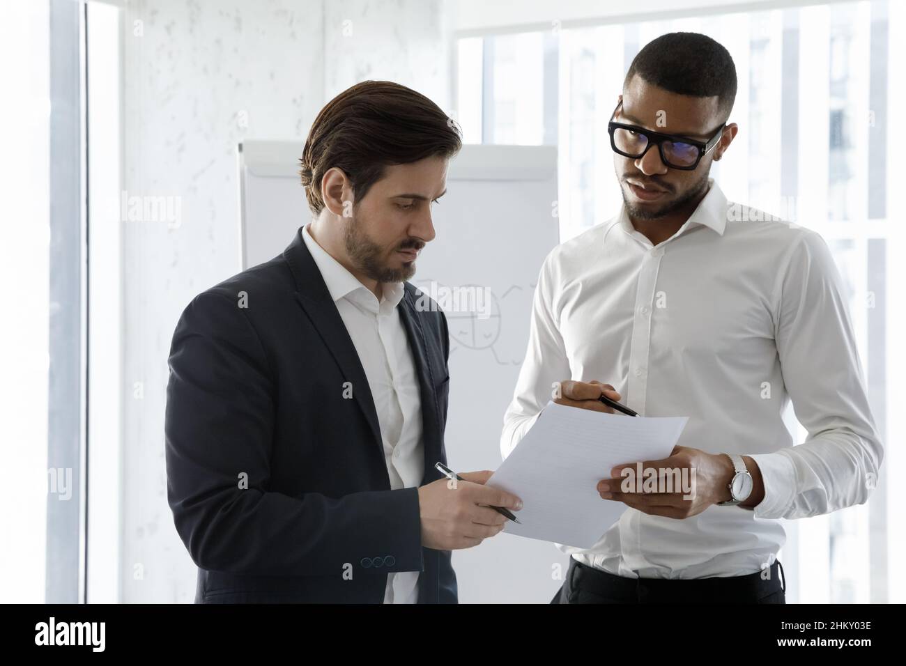 Multiethnische Millennials Mitarbeiter Männer lesen zusammen Papier Stockfoto